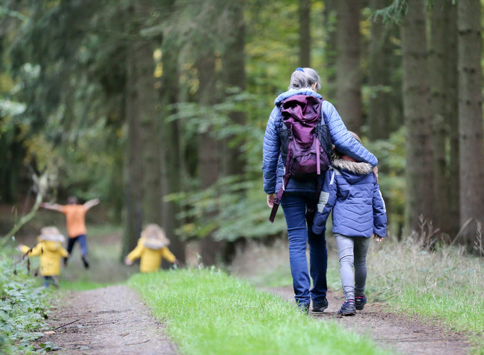 Randonnée en famille sur un chemin forestier, un adulte avec sac à dos et des enfants