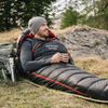 Randonneur allongé dans un sac de couchage grand froid au bivouac