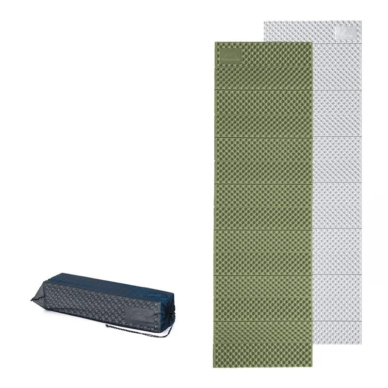 Matelas de camping en mousse pliable vert et argenté, posés à plat à côté du matelas replié dans sa housse