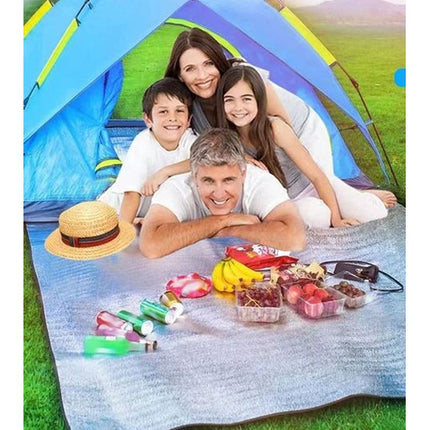 Famille installée sur le tapis de sol devant une tente de camping